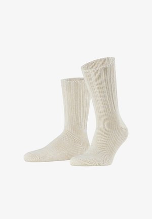 Chaussettes beige à côtes fabriquées à partir d'un matériau texturé, avec un design montante jusqu'au genou, des poignets renforcés et une zone des orteils lisse.