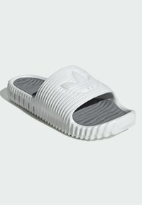 Vita skum sandaler i vit med räfflad ovandel, öppen tådesign, grå texturerad innersula och subtil logotypdetalj på toppen.