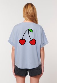  Lichtblauw shirt met korte mouwen en een ronde hals, met op de achterkant een zwarte omlijning van twee rode harten en een groen blad.