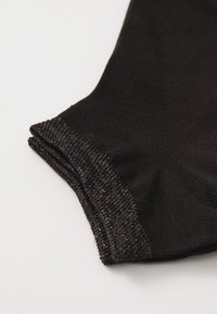 Fekete leggings, textúrált, sima felülettel. Finom, fényes szegélydíszítéssel az alsó részen, rugalmas anyagból készült.