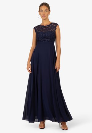 Abendkleid in Marineblau mit einem Spitzenoberteil und kurzen Ärmeln, einem fließenden Rock und einer taillierten Taille. Glatte Textur mit filigranen Details.