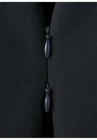 Deux curseurs de fermeture éclair noirs proches l'un de l'autre sur un tissu foncé texturé, montrant l'écart central entre les sections zippées.