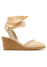 Beżowe skórzane sandały na koturnie z okrągłym noskiem, z jucianym obcasem oraz dekoracyjnymi paskami wstążkowymi, które wiążą się wokół kostki.