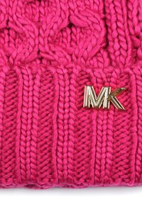 Różowa dziana czapka z teksturowanym wzorem i wyraźnym złotym logo "MK". Grube włókna nadają jej ciepły i przytulny wygląd.