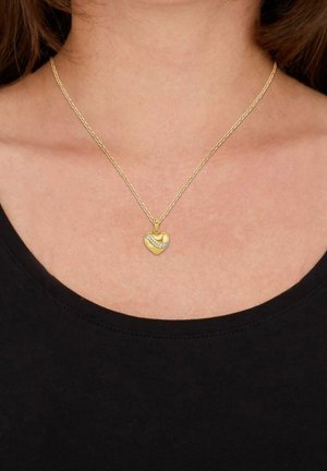 Collar con colgante en forma de corazón dorado con acentos brillantes, que presenta una superficie texturizada y un diseño retorcido en una delgada cadena de oro.