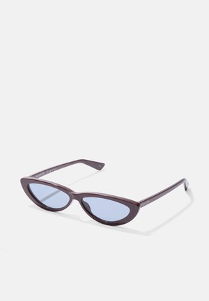 Ochelari de soare tip cat-eye cu un cadru din plastic maron și lentile de culoare albastră deschisă. Brațele subțiri se extind dintr-un pod curbat, având un branding subtil.