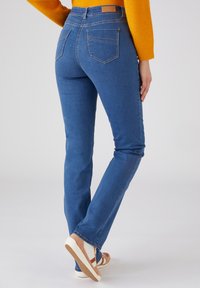 Jean en denim bleu avec une coupe slim, un design à cinq poches et des coutures discrètes. Le tissu est lisse avec une légère élasticité pour le confort.