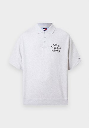 Svetlo siva polo majica z kratkimi rokavi, ovratnikom in tremi gumbi, z napisom "Tommy Jeans" in logotipom na prsih ter majhnim logotipom na rokavu.