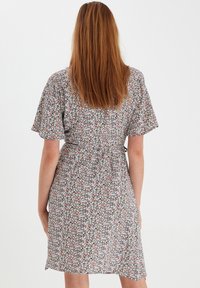 Vestido wrap floral con mangas cortas, que presenta un estampado multicolor sobre un fondo claro y un detalle de cintura ceñida.