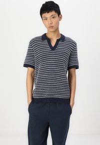Polo en tricot rayé bleu marine et blanc avec des manches courtes, col en V, tissu texturé et bords côtelés à l'ourlet et au col.