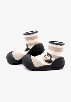 Las suaves botitas de tela presentan un diseño a rayas en beige y crema con un motivo de pingüino. La suela de goma negra proporciona agarre y durabilidad.