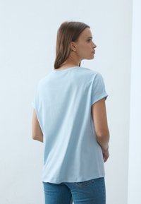 Lyseblå t-shirt med korte ærmer, afslappet pasform og opsmøgede ærmer. Fremstillet af glat stof, med et enkelt og rent design.