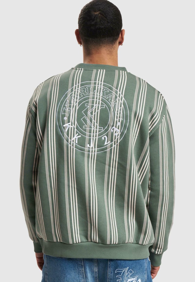Maglione verde a righe con linee verticali bianche e un logo circolare sul retro, dotato di polsini e orlo a coste. Tessuto casual e texturizzato.