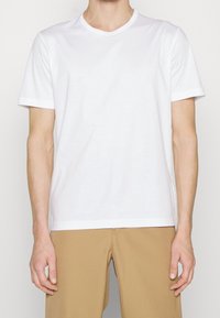 White cotton t-shirt with short sleeves, a round neckline, and a straight hem. Fabric appears soft with a smooth texture and no patterns.