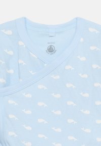 Φως γαλάζιο βρεφικό φορμάκι με λευκό σχέδιο φάλαινας, μέγεθος 6 μηνών, κατασκευασμέν ο από την Petit Bateau.