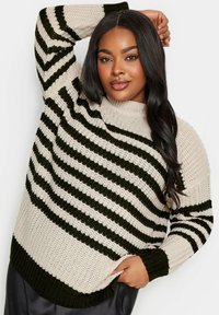 Stickad tröja med en krämfärgad bas och mörkgröna ränder, ribbade muddar och en bred, mysig halsringning. Strukturerad tyg med lös stickning.