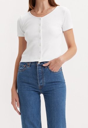 Wit geribd short-sleeve top met een ronde hals en zes knopen aan de voorkant, gecombineerd met blauw denim spijkerbroek met een klassieke pasvorm en normale taille.