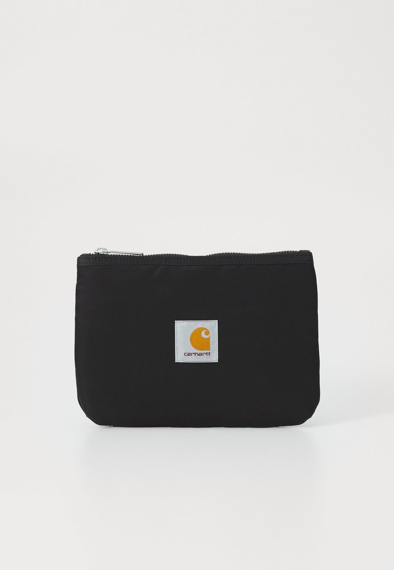 Pochette noire à fermeture éclair en tissu durable, présentant un patch carré avec un logo orange sur fond blanc. Texture lisse.