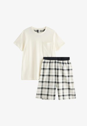 T-shirt crème à manches courtes avec poche poitrine, associé à un short à taille élastique à carreaux noir et blanc.