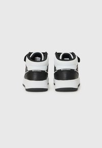 Baskets montantes noir et blanc avec une semelle texturée et un logo à l'arrière, présentées de dos sur un fond clair.