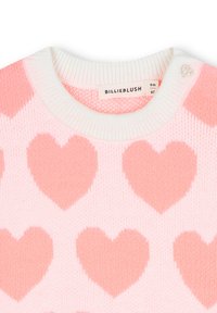 Maglione rosa con grandi motivi a cuore di un rosa chiaro, colletto bianco a coste e dettaglio di bottone decorativo sulla spalla. Texture a maglia morbida.