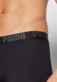 Fekete pamut boxernadrág, széles gumis derékkal, amelyen a "PUMA" logo fel van emelve. Sima textúra és testhezálló kialakítás.