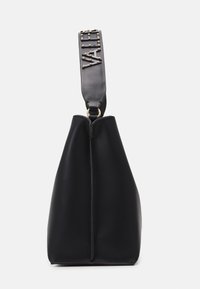 Black bag with a structured shape, made of smooth leather. Features a decorative strap with studs and a logo, attached with a gold ring.