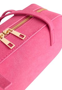 Fuksjowa torebka z zamszu z złotym zamkiem błyskawicznym, o wyraźnym kształcie i podwójnymi uchwytami, podkreślająca gładką teksturę i minimalistyczny design.