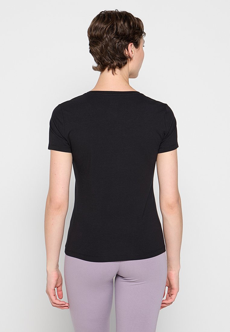 Czarny dopasowany t-shirt z krótkim rękawem z miękkiej bawełnianej dzianiny, okrągły dekolt, gładka tekstura, noszony z jasnofioletowymi legginsami.