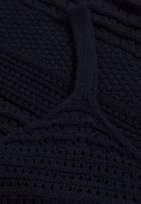 Laivaston sininen neulepusero, jossa on teksturoitu kuosi, joka sisältää pystysuuntaisia ja vaakasuoria viivoja. Puserossa on pyöreä kaula-auko ja paksut ribbauspinnat.