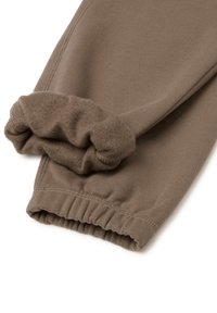 Braune Baumwoll-Sweatpants mit einem weichen, strukturierten Bund. Der Knöchel hat ein gerafftes Elastikband, und die Nähte sind ordentlich verarbeitet.