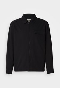 Black long-sleeve shirt featuring a collared neckline, front zip closure, and a chest pocket. Made of textured fabric with a relaxed fit.