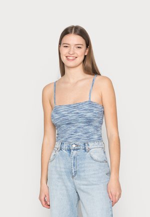 Top de alças finas em azul com textura canelada, apresentando um design ajustado, combinado com jeans de cintura alta em lavagem clara.
