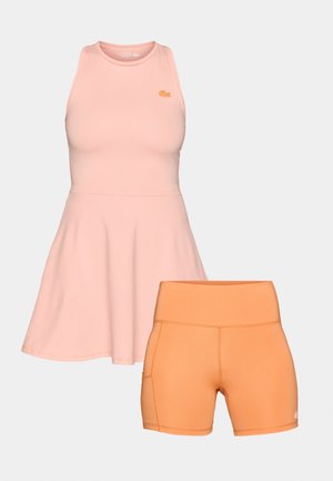 Roza brezrokavna športna obleka s krožno krilo in oranžni visok pas kratke hlače, oboje narejeno iz gladkega, raztegljivega materiala.