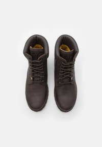 Botas de cuero marrón hasta el tobillo con diseño de cordones, collar acolchado y forro interior amarillo. Presentan un acabado texturizado y ojales reforzados.