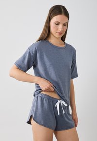 Grau T-Shirt mit kurzen Ärmeln und passende Shorts aus weichem Stoff. Die Shorts haben einen elastischen Bund mit Kordelzug und seitliche Schlitze für mehr Bewegungsfreiheit.