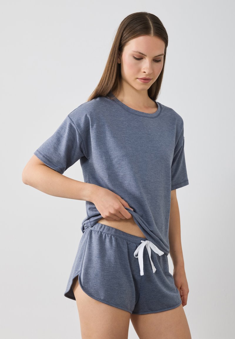 Grau T-Shirt mit kurzen Ärmeln und passende Shorts aus weichem Stoff. Die Shorts haben einen elastischen Bund mit Kordelzug und seitliche Schlitze für mehr Bewegungsfreiheit.