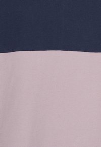 Tissu bicolore avec une partie supérieure bleu marine et une partie inférieure mauve clair, montrant la texture et le contraste des couleurs.