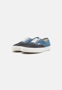 Sneaker in denim con un motivo a strisce blu e nere, lacci bianchi e suole in gomma. Punta arrotondata e design casual.