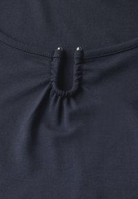 Tela de color azul marino con un diseño fruncido en el centro, que cuenta con dos acentos metálicos. Textura suave y superficie lisa.