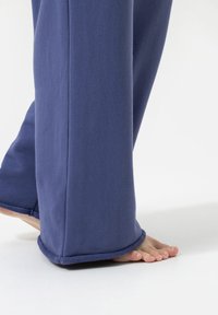 Paarse fleecebroeken met een wijd ontwerp, met een gladde textuur en een zoom met een subtiele gestikte detail aan de onderkant.