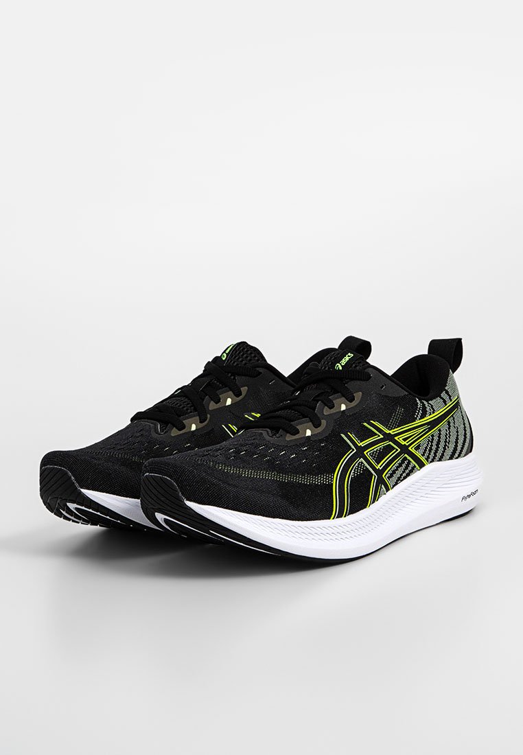 Zapatillas deportivas negras con detalles verdes, parte superior de tejido texturizado, entresuela blanca y suela exterior negra. Presentan un diseño transpirable y un sistema de cordones.