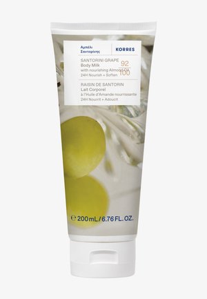 Tube blanc présentant l'étiquette de Lait Corps au Raisin de Santorin. Les éléments clés incluent des images de raisins verts et un texte bleu. Contient 200 ml.
