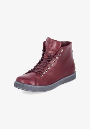 Hoge donkerrode leren sneaker met zwarte zool en zwarte veters, iets schuin naar rechts op een witte achtergrond.