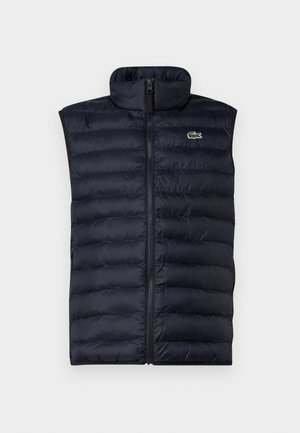 Navy puffer vest with high collar, front zipper, and horizontal quilted pattern. Features a small green logo on the upper left side.
