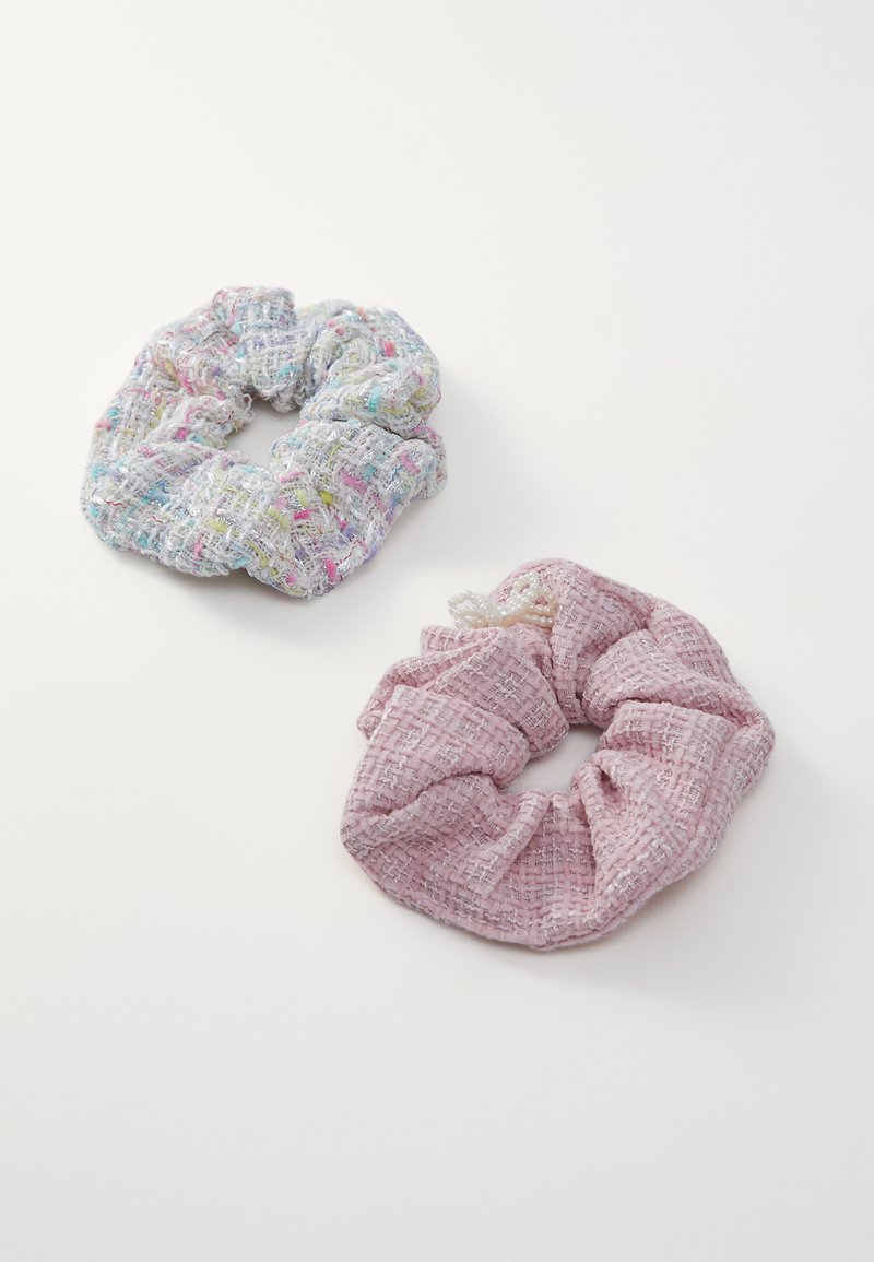 Két szövet hajgumit láthatunk: az egyik színes, szőtt mintájú, a másik egyszínű pasztell rózsaszín, texturált felülettel. Mindkettő puha és rugalmas.