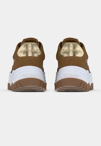 Καφέ σουέντ αθλητικά παπούτσια με χρυσές λεπτομέρειες στη φτέρνα, λευκή ενδιάμεση σόλα και υφασμένο καφέ λαστιχένιο πέλμα, με ανάγλυφο λογότυπο επωνυμίας.