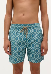 Shorts de bain teal avec un motif de vagues blanches et de petits motifs de crânes. Taille élastique avec cordon de serrage, tissu léger, coupe mi-genoux.