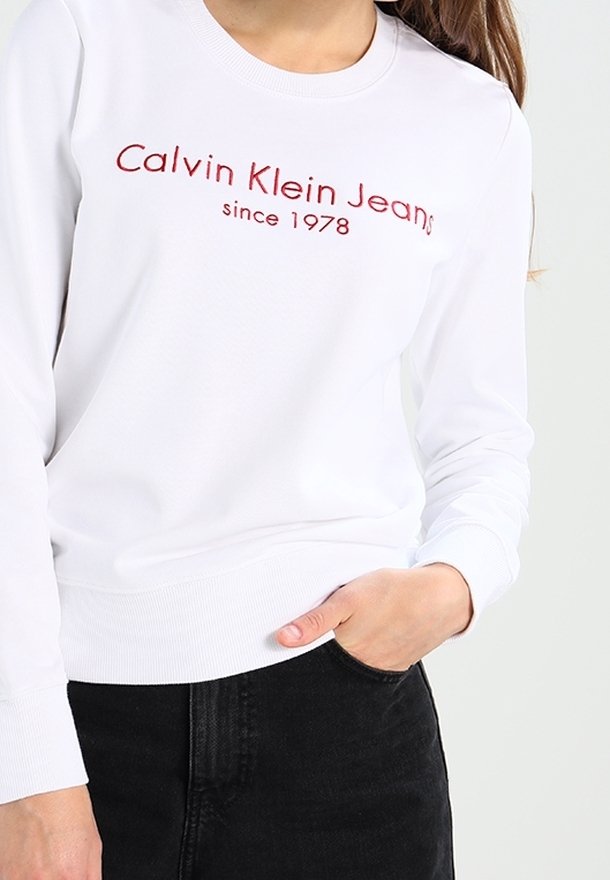Felpa bianca a maniche lunghe con logo ricamato rosso "Calvin Klein Jeans dal 1978"; polsini e orlo a coste. Tessuto semplice.