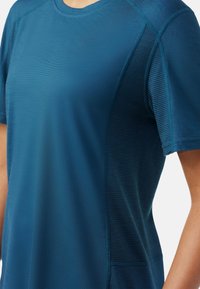 Korteærmet sports T-shirt i mørk teal, med glat stof og strukturerede paneler på siderne, samt rund hals og syninger.